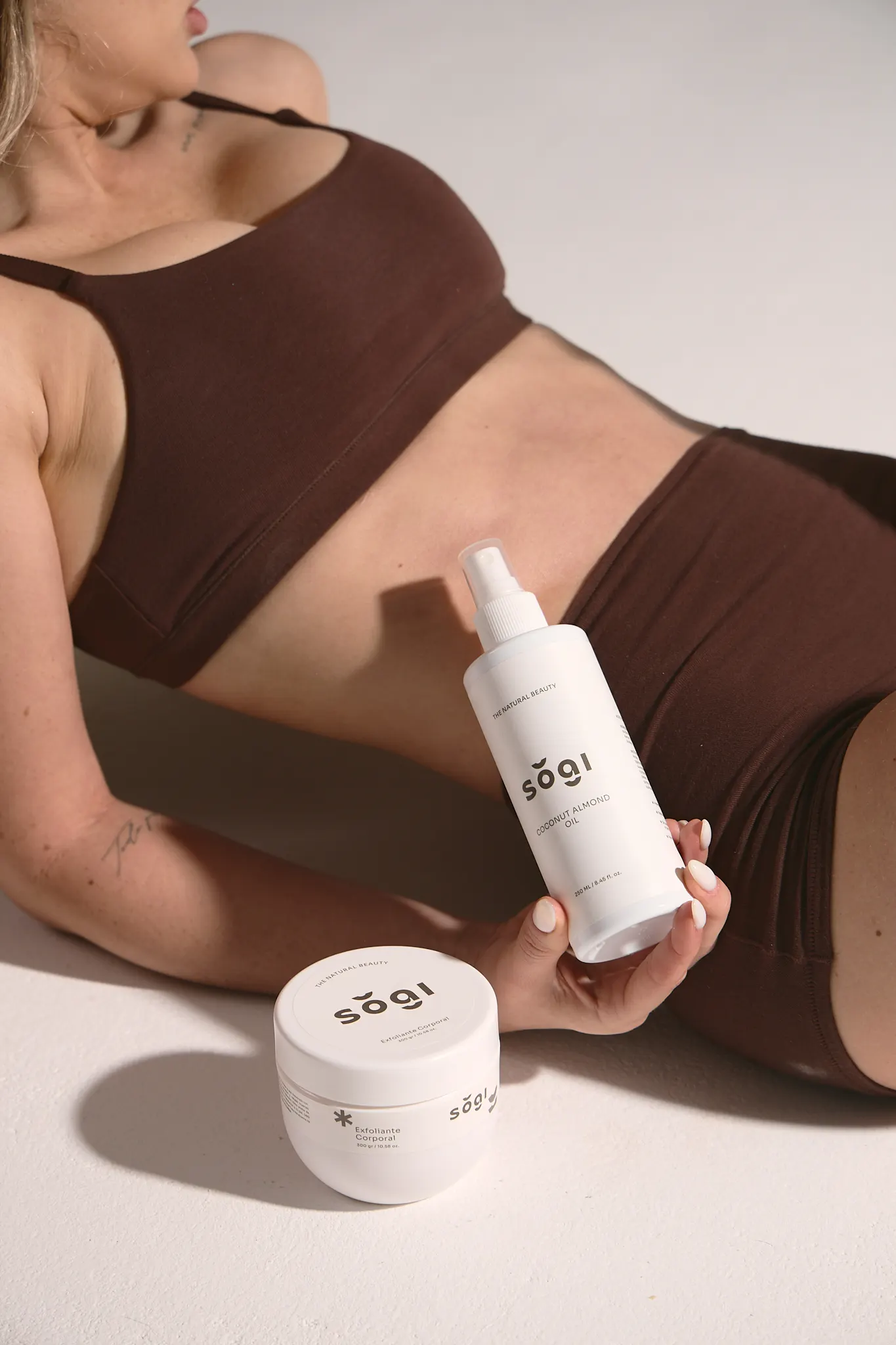 Modelo sosteniendo el aceite corporal y el exfoliante sŏgi.